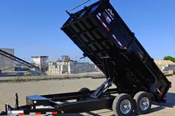 Black Utility Trailer with Raised Dump Bed in Industrial Area